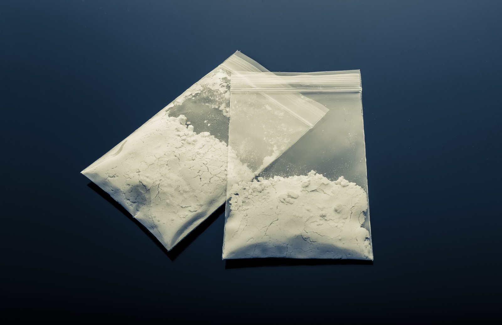 ジップロック袋に入った白い粉状の物質が紺色の背景に置かれている